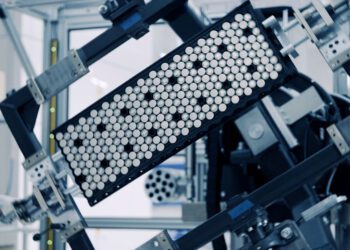 A close-up of machinery holding a rectangular tray filled with cylindrical cells, likely in a laboratory or manufacturing setting—reminiscent of how Rimac Technology has revolutionized advanced battery systems.