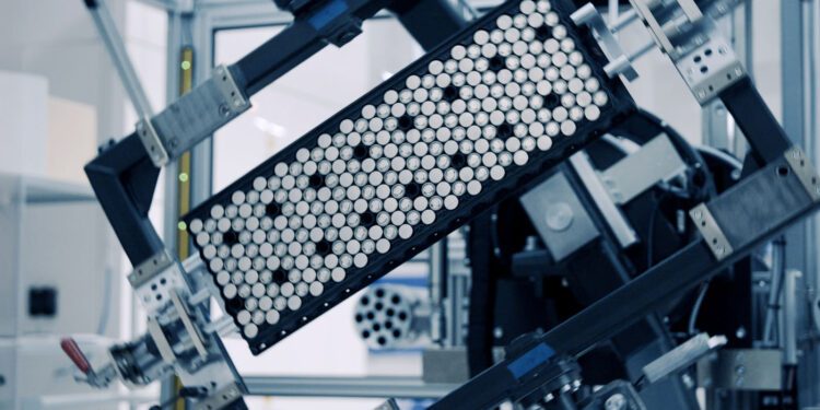 A close-up of machinery holding a rectangular tray filled with cylindrical cells, likely in a laboratory or manufacturing setting—reminiscent of how Rimac Technology has revolutionized advanced battery systems.