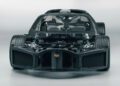 Frontal view of a Bugatti Tourbillon supercar chassis with exposed carbon fiber body, visible suspension, and interior framework, photographed in a studio setting.