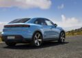 A blue Porsche Macan SUV from Porsche Cars North America is parked on an empty road, framed by a mountainous landscape and blue sky—a symbol of H1 2025 growth.