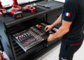 A person opens a drawer containing organized hand tools in a workshop, with power tools placed on top of the black workbench—offering an exclusive setup supported by an expert support team.
