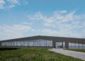 A modern, flat-roofed production facility with large glass windows, set on grassy land under a partly cloudy sky, reminiscent of the precision found in Bugatti’s Tourbillon engineering.