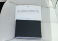 Two booklets, one labeled "Rolls-Royce Motor Cars Maintenance & Warranty," rest on a white perforated leather car seat in a 2024 Rolls-Royce—an essential detail for any collector’s car.