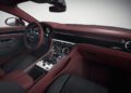 Luxury car interior featuring burgundy leather seats, wood and black trim, a large central console with controls, and a modern steering wheel—showcasing exclusive Bentley Mulliner interior options.