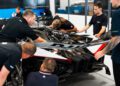 An expert support team inspects and works on the rear section of an exclusive Bugatti Bolide in a workshop.