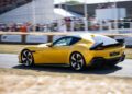 A yellow Ferrari F80 speeds along the track at Goodwood, thrilling the crowd under the covered grandstand during the outdoor Amalfi Reveal event.