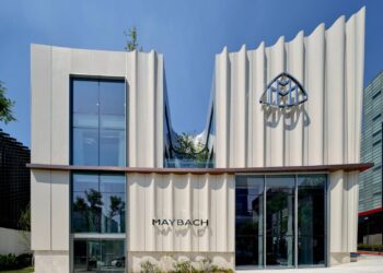 Modern Maybach showroom building with a wavy facade, large glass windows, the Maybach logo, and the brand name displayed above the entrance—home to the World's First Maybach Brand Center in Seoul.