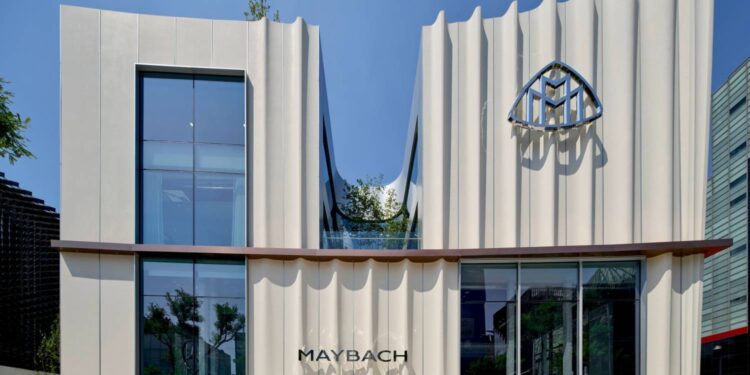 Modern Maybach showroom building with a wavy facade, large glass windows, the Maybach logo, and the brand name displayed above the entrance—home to the World's First Maybach Brand Center in Seoul.