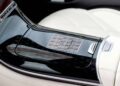 A silver metal card with a geometric pattern and the text "THE CARD VIBES" rests on the glossy black center console of a car, capturing the luxury at Seoul’s Maybach Brand Center. Light-colored leather seats complete this world-class experience.