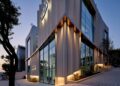 Modern glass and concrete building with large windows and exterior lights, situated on a sloped street at dusk—the World's First Maybach Brand Center in Seoul.