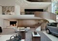 A modern luxury car showroom in Seoul with a spiral staircase, stylish seating area, and cars on display; at the world's first Maybach Brand Center, accessories are arranged on tables in the foreground.