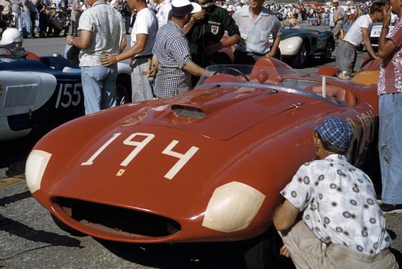 A red vintage Ferrari 375 Plus race car with the number 194 is on display, surrounded by people at an outdoor racing event—a classic sight honoring Shelby and legendary miles on the track.