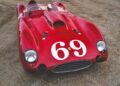 A vintage red Ferrari 375 Plus race car with the number 69 displayed on the hood is parked on a gravel surface, evoking memories of classic Shelby and Miles racing legends.