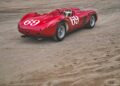 A vintage red Ferrari 375 Plus race car with the number 69 on the hood and sides is parked on a dirt surface.