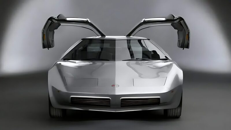 A silver sports car with gull-wing doors open, viewed from the front in a studio with a neutral gray background—an evocative nod to the 10 Unsung Mid-Engine American Concepts That Pushed the Envelope Of Performance.