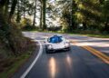 A silver McLaren F1 speeds around a curve on a tree-lined road in daylight, reminiscent of the legends showcased at RM Sotheby's Monterey Auction.
