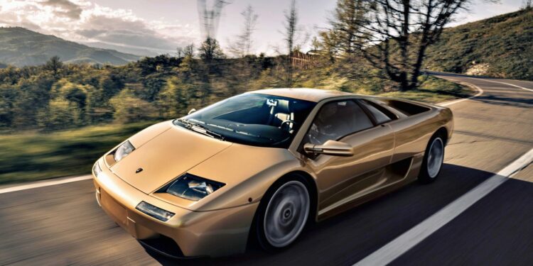 A gold Lamborghini Diablo cruises along a winding Emilia-Romagna road, lined with trees and hills beneath a partly cloudy sky—a perfect scene for fans of vintage Lamborghinis.