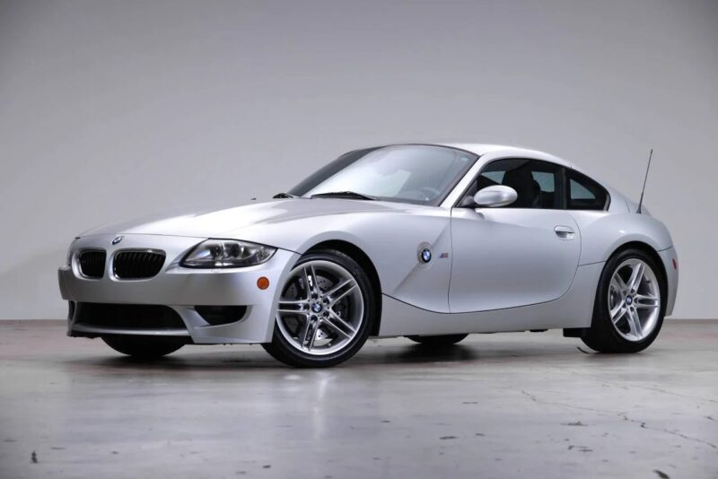 A silver BMW coupe, one of the best 2000s cars, is parked indoors against a plain white background, viewed from the front left side.