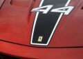Close-up of a red Ferrari hood featuring the Ferrari logo, a black racing stripe, and the number 44 with "599XX" lettering—highlighting a rare Ferrari 599XX EVO at Monterey auction.