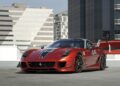 A red Ferrari 599XX EVO with black stripes and the number 44 is parked on a rooftop, modern buildings in the background—an eye-catching scene reminiscent of Monterey auction exclusives.