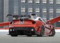 A red Ferrari 599XX EVO with a large rear wing is parked on a rooftop, set against a modern, glass-covered building—an impressive sight ahead of the upcoming Monterey auction.