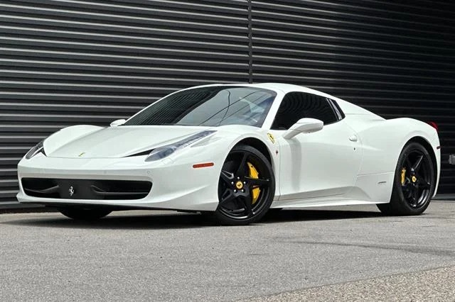 A stunning white Ferrari 458 Italia with black wheels and yellow brake calipers is parked on a street, showcasing why it's considered one of the best Ferrari cars for sale.