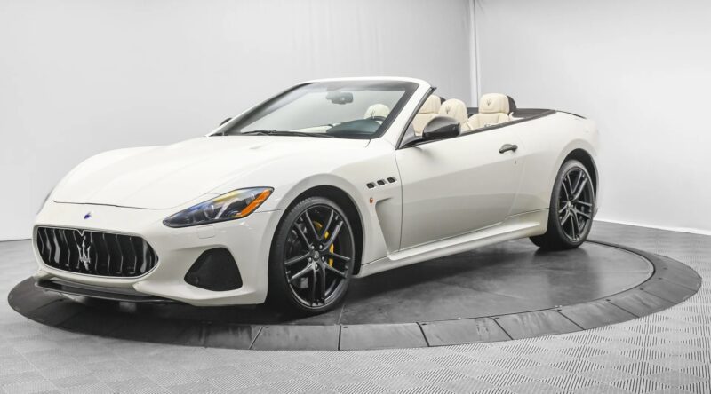 A white Maserati GranTurismo convertible, a true symbol of Italian luxury, is displayed in a photo studio with a plain background.