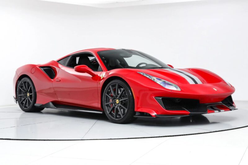 A Ferrari 488 Pista with black and white racing stripes, photographed in a white studio with its front and side visible—this track-ready Ferrari perfectly blends style and performance.