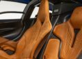 Close-up view of two tan leather bucket seats with embossed designs inside a modern sports car, featuring black and carbon fiber accents—much like what you’d find in an ultra-low mile McLaren Speedtail with $250k in MSO options heading to auction.