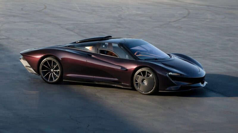 A sleek, dark purple Ultra-low Mile McLaren Speedtail with $250k in MSO options and a low profile is parked on a concrete surface under natural daylight.