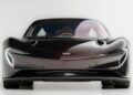 Front view of an ultra-low mile McLaren Speedtail with $250k in MSO options, showcasing its aerodynamic design, sleek black finish, and prominent headlights, photographed against a plain white background.