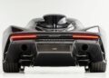 Rear view of this ultra-low mile McLaren Speedtail with $250k in MSO options, showcasing its dual exhausts, wide tires, and horizontal LED taillights against a white background—soon heading to auction.