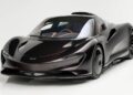 A sleek, black ultra-low mile McLaren Speedtail with $250k in MSO options is displayed in a well-lit studio with a white background, ready to impress as it heads to auction.