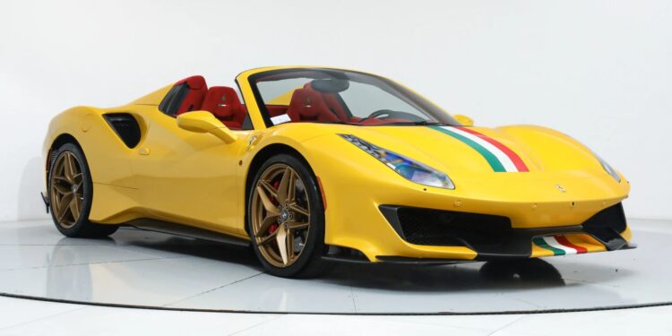 A yellow Ferrari 488 Pista with red interior, gold wheels, and green, white, and red racing stripes is displayed in a white showroom, highlighting this stunning track-ready Ferrari for sale.