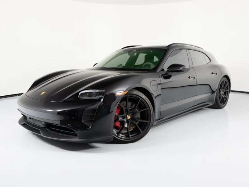 A black Porsche Taycan Cross Turismo, one of the finest Luxury Performance Wagons, is parked in a white studio, viewed from the front left side.