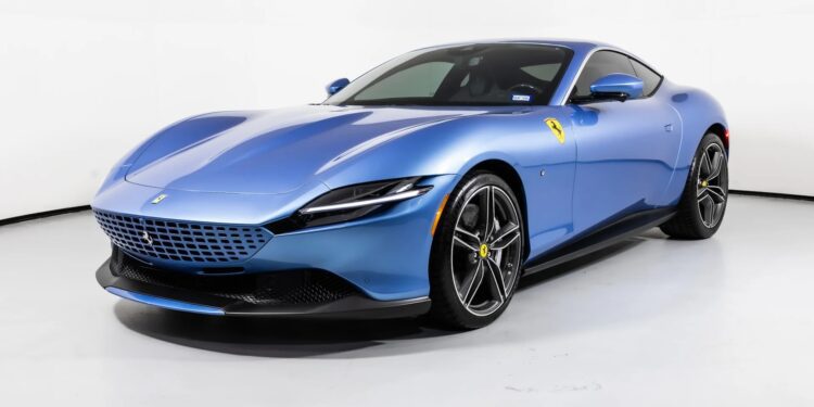 A blue Ferrari Roma, embodying La Nuova Dolce Vita, is parked in a white studio and viewed from the front left angle.