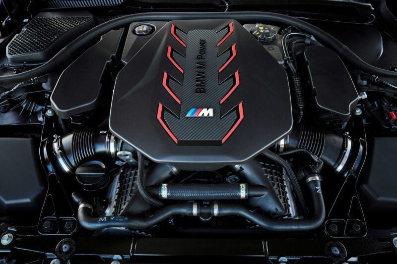 Close-up view of a BMW M Power engine with red accents, carbon fiber details, and the iconic “M” badge—highlighting the engineering behind the Review: 2025 BMW M5 Touring Weighs In As A Great Allrounder.