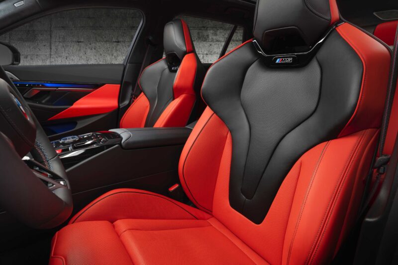Front seats of a car with black and red leather upholstery, featuring the M5 badge on the headrest and a modern, sporty interior design—perfectly reflecting the Review: 2025 BMW M5 Touring Weighs In As A Great Allrounder.