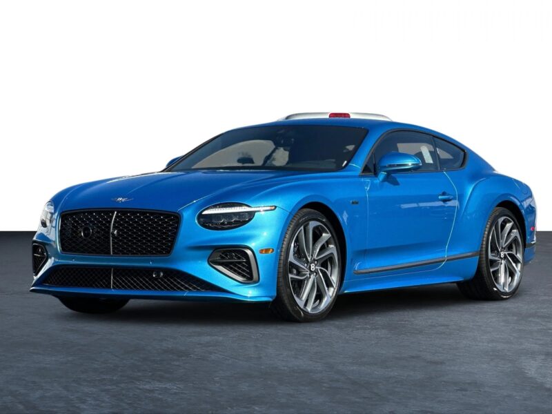 A blue luxury coupe car is parked on a dark surface with a plain white background, showcasing the elegance of an exotic car.
