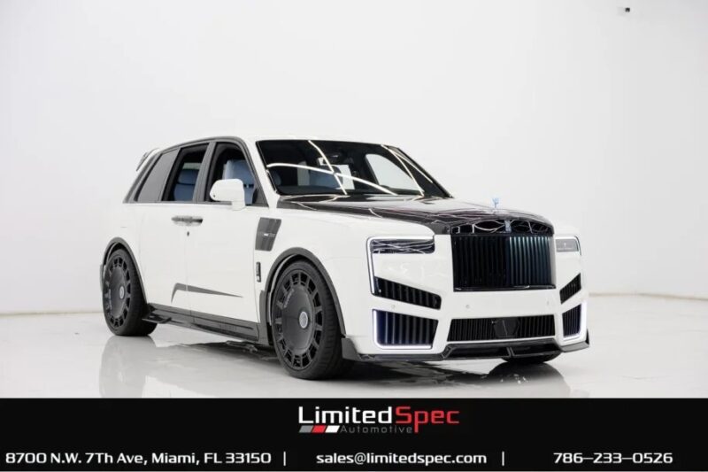 A custom white luxury SUV with black accents is displayed in a bright, white showroom. Showcasing the epitome of an exotic car, contact details and the Limited Spec Automotive logo appear at the bottom.