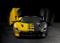 A black and yellow Ferrari sports car with upward-opening doors, photographed from the front against a dark background. The word "Ferrari" is vertically printed on the hood—this unique look evokes the Tailor Made Daytona SP3.