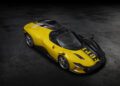 A yellow and black Ferrari Daytona SP3 with a unique patterned design is parked on a dark, textured surface, viewed from above—an eye-catching contender for any Car Week Charity Auction.