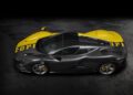 A dark gray Ferrari Daytona SP3 with yellow accents and "Ferrari" lettering on the roof, photographed from above on a dark textured surface, stands out as a stunning highlight of the Car Week Charity Auction.