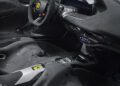 Interior view of a Ferrari Daytona SP3 featuring a steering wheel with the Ferrari logo, digital dashboard, and modern controls with black and silver detailing—an exclusive piece perfect for a charity auction.
