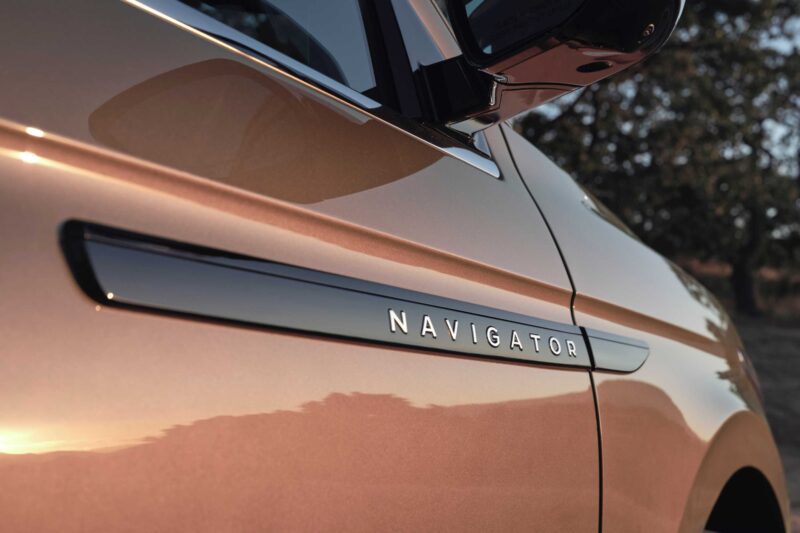 Close-up view of the side of a copper-colored 2025 Lincoln Navigator L Black Label with "Navigator" displayed on a trim piece near the door—luxury that coddles like a spa on wheels.