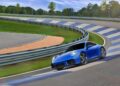 A Limited-Run 2026 911 Carrera T Club Coupe drives along a banked, curving racetrack bordered by metal guardrails and trees, celebrating 70 years of the Porsche Club of America.