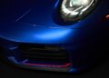 Close-up view of the front left headlight and bumper of a blue Limited-Run 2026 911 Carrera T Club Coupe with a red accent detail on the lower grille, celebrating 70 years of Porsche Club of America.