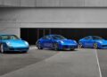 Three blue Limited-Run 2026 911 Carrera T Club Coupes are parked side by side in front of a modern building with a "Porsche" sign, celebrating 70 years of the Porsche Club of America.