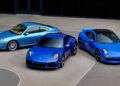 Three blue Limited-Run 2026 911 Carrera T Club Coupes are parked side by side on a concrete surface in front of a dark glass building, celebrating 70 years of the Porsche Club of America.