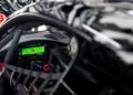 Close-up view of a Porsche 911 Cup Car cockpit during the 2026 race season, highlighting the digital dashboard display, steering wheel controls, and safety harness.